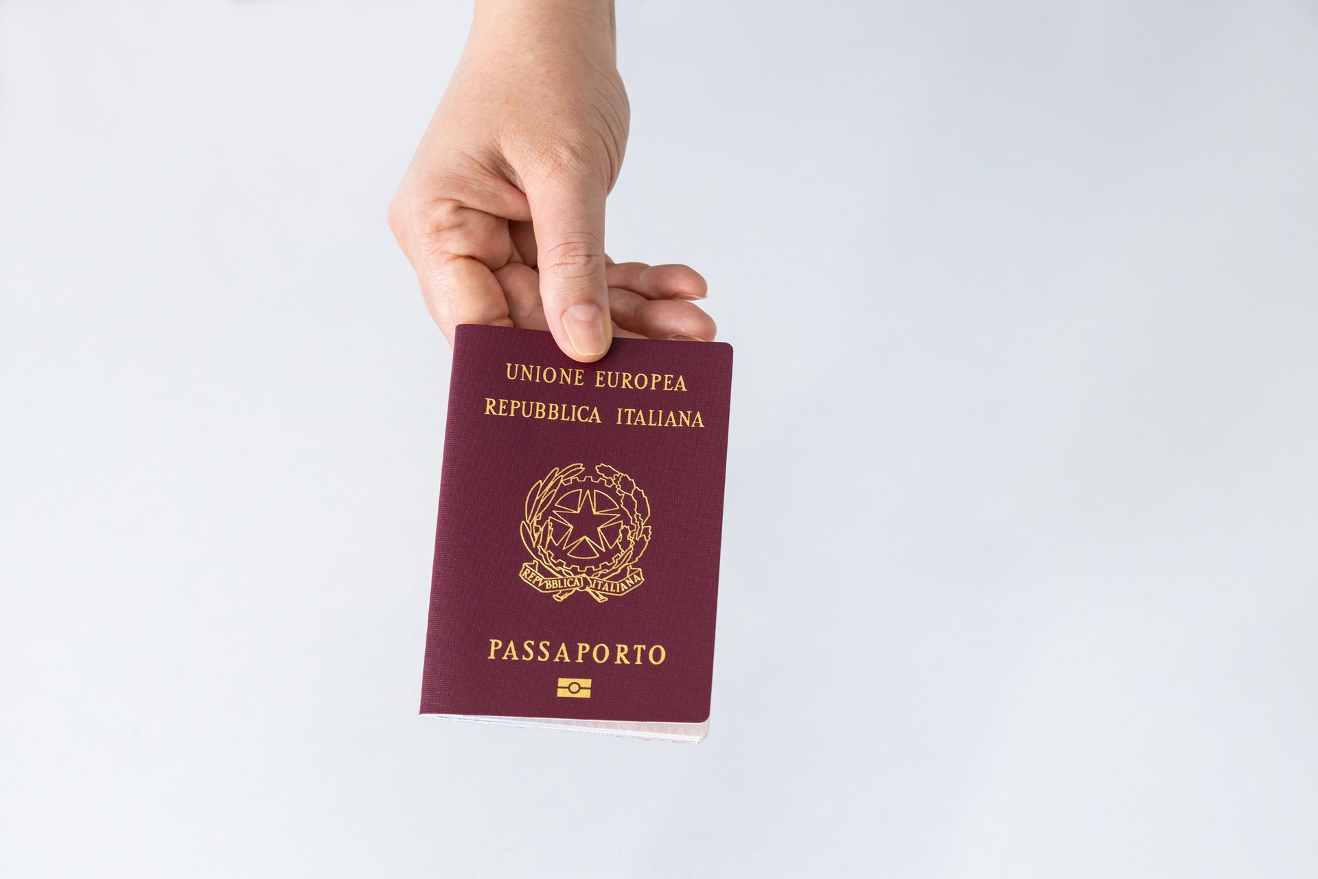 Mão segurando um passaporte italiano